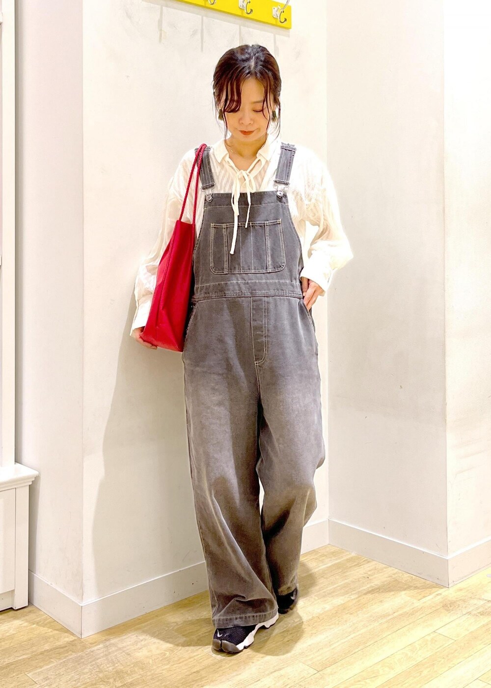 レッド系のトートバッグ、ホワイト系のシャツ/ブラウス、ブラック系のサロペット/オーバーオールを着用したレディースの秋コーディネートの3枚目の写真