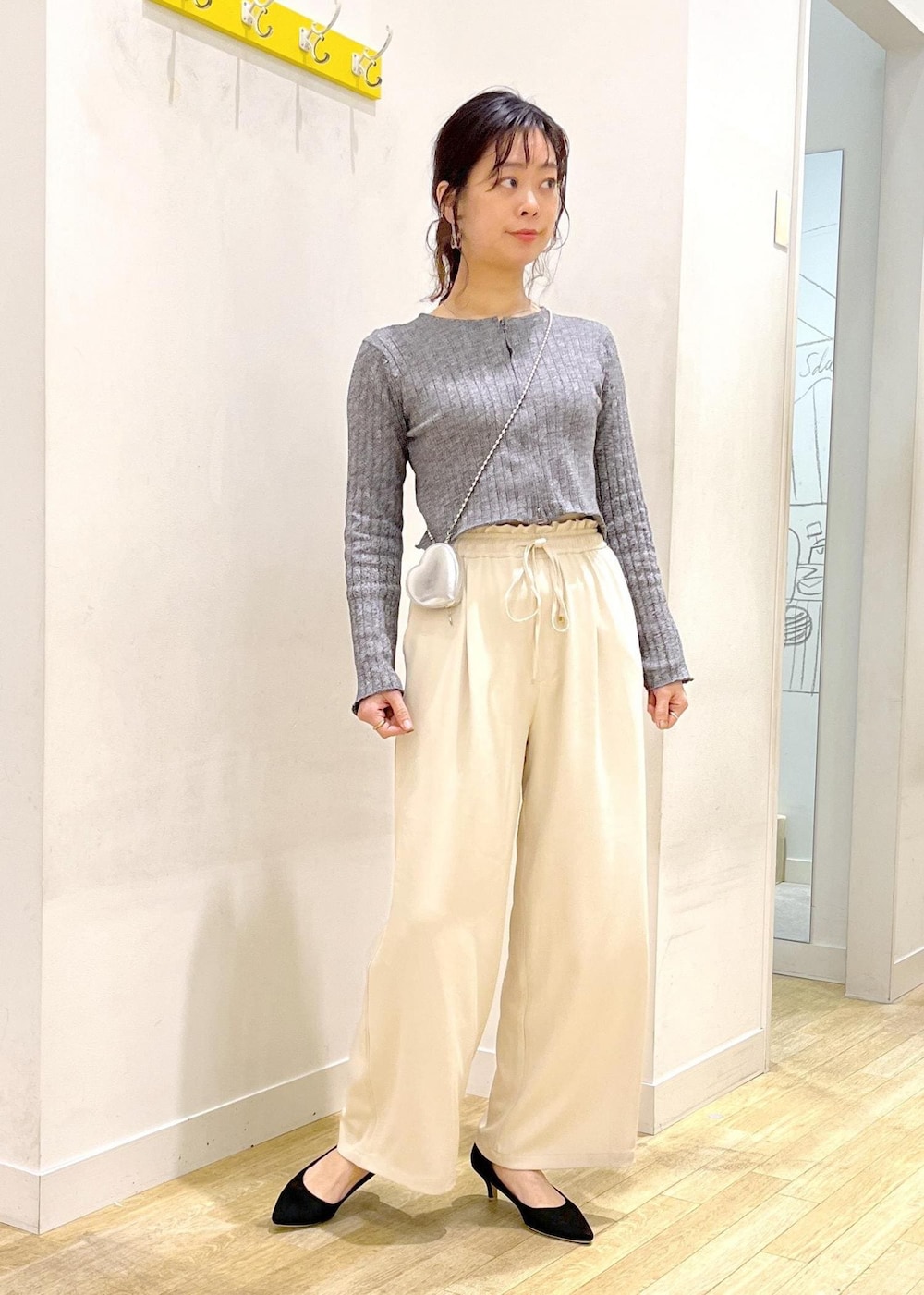 ブラック系のパンプス、シルバー系のショルダーバッグ、ブラック系のニット/セーターを着用したレディースの春コーディネートの2枚目の写真