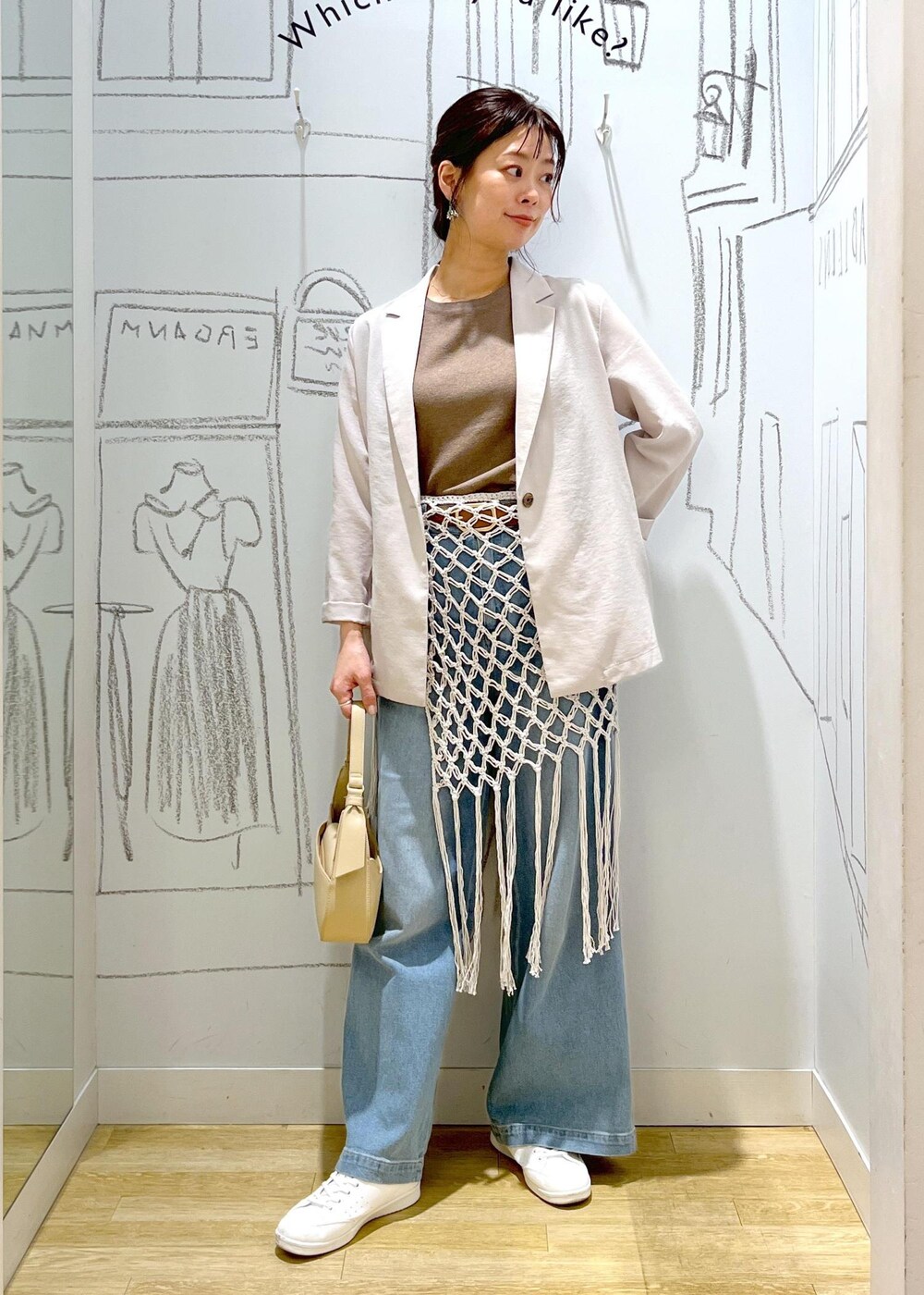 ベージュ系のハンドバッグ、ブルー系のデニムパンツ、ホワイト系のスカートを着用したレディースの春コーディネートの2枚目の写真