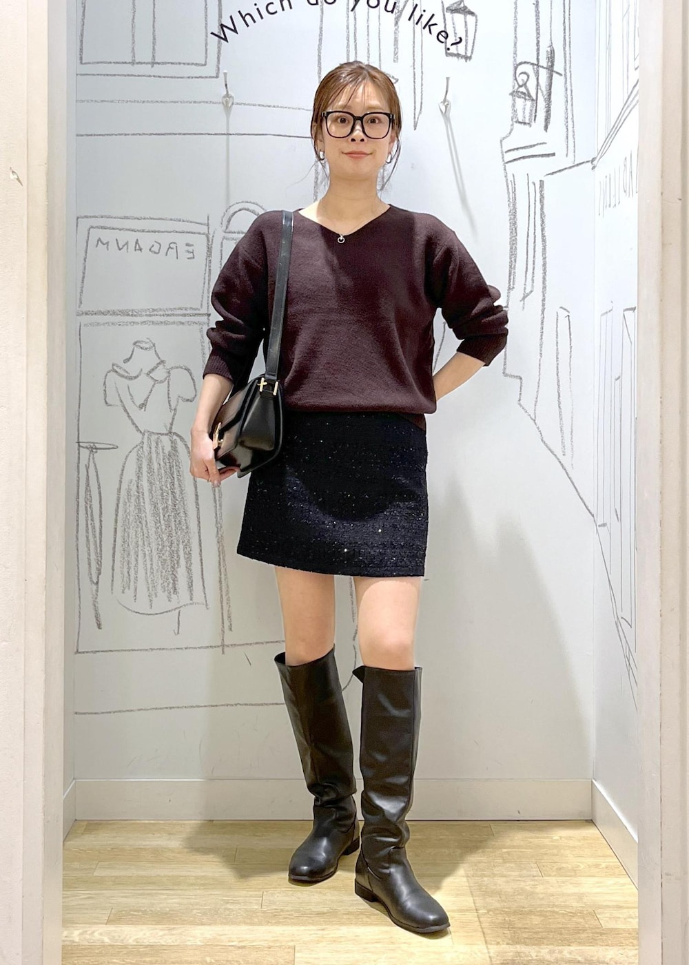 ブラック系のショルダーバッグ、ブラウン系のニット/セーター、ブラック系のダウンジャケット/コートを着用したレディースの冬コーディネートの2枚目の写真