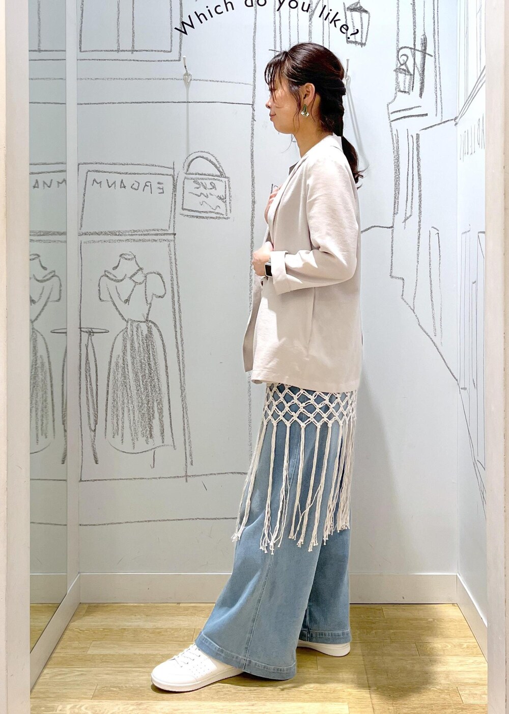 ベージュ系のハンドバッグ、ブルー系のデニムパンツ、ホワイト系のスカートを着用したレディースの春コーディネートの4枚目の写真