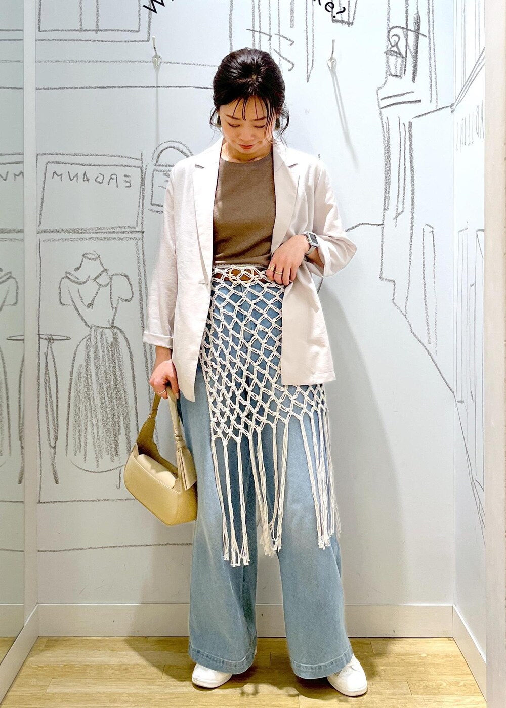 ベージュ系のハンドバッグ、ブルー系のデニムパンツ、ホワイト系のスカートを着用したレディースの春コーディネートの3枚目の写真