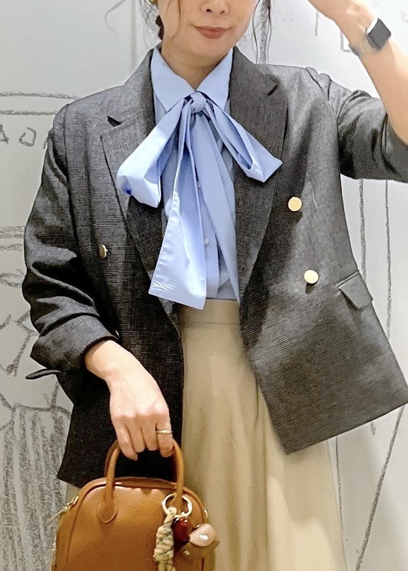 グレー系のテーラードジャケット、ベージュ系のスカート、ブラウン系のパンプスを着用したレディースの秋コーディネートの7枚目の写真