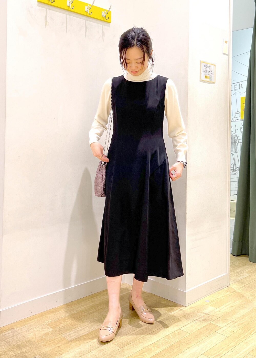 ホワイト系のニット/セーター、ブラック系のドレス、パープル系のショルダーバッグを着用したレディースの冬コーディネートの3枚目の写真