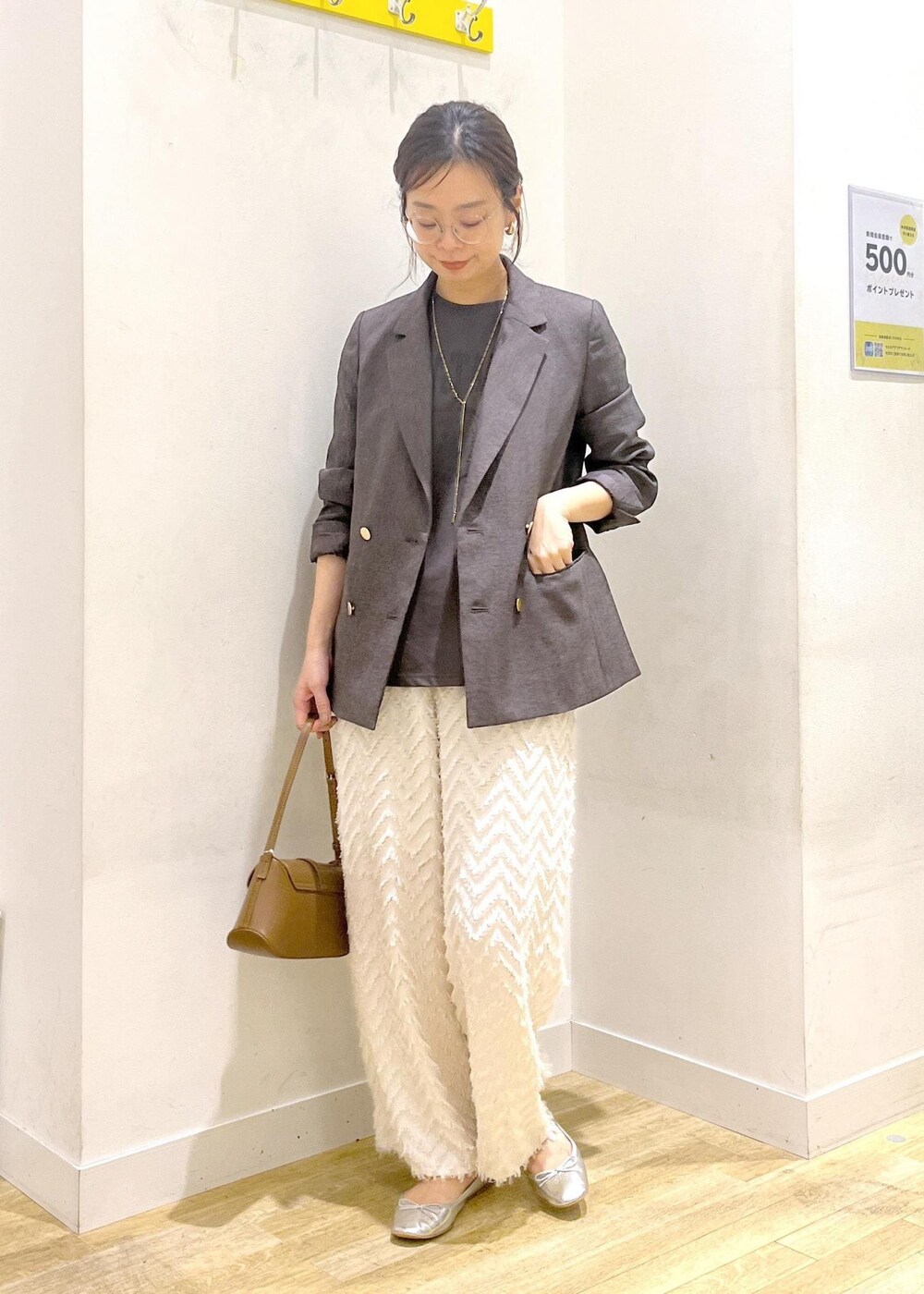 ブラウン系のテーラードジャケット、ブラウン系のショルダーバッグ、グレー系のTシャツ/カットソーを着用したレディースの秋コーディネートの2枚目の写真