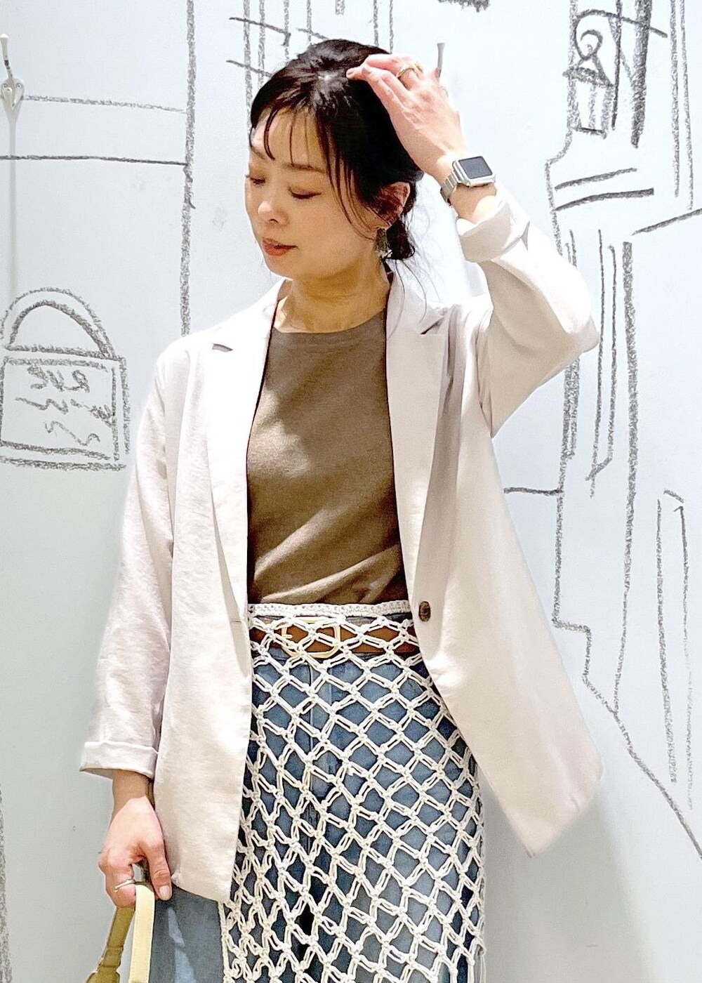 ベージュ系のハンドバッグ、ブルー系のデニムパンツ、ホワイト系のスカートを着用したレディースの春コーディネートの7枚目の写真