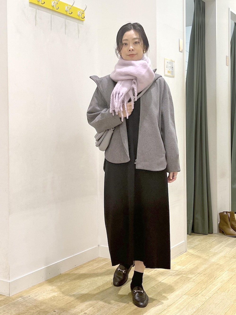 ブラック系のジャンパースカート、ブラウン系のその他アウター、グレー系のショルダーバッグを着用したレディースの冬コーディネートの2枚目の写真