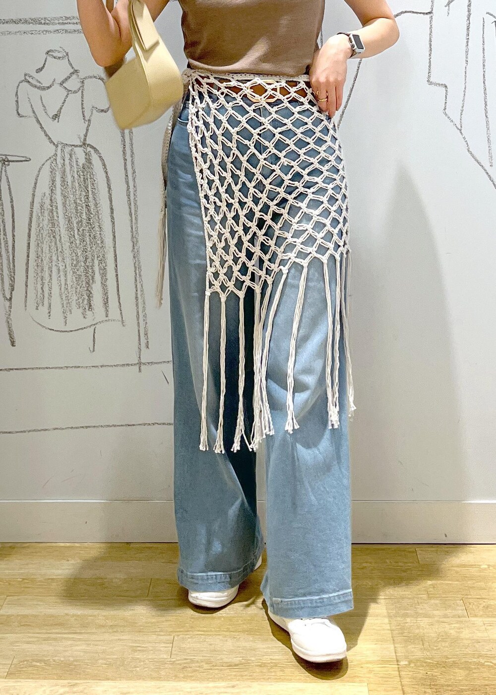 ベージュ系のハンドバッグ、ブルー系のデニムパンツ、ホワイト系のスカートを着用したレディースの春コーディネートの8枚目の写真