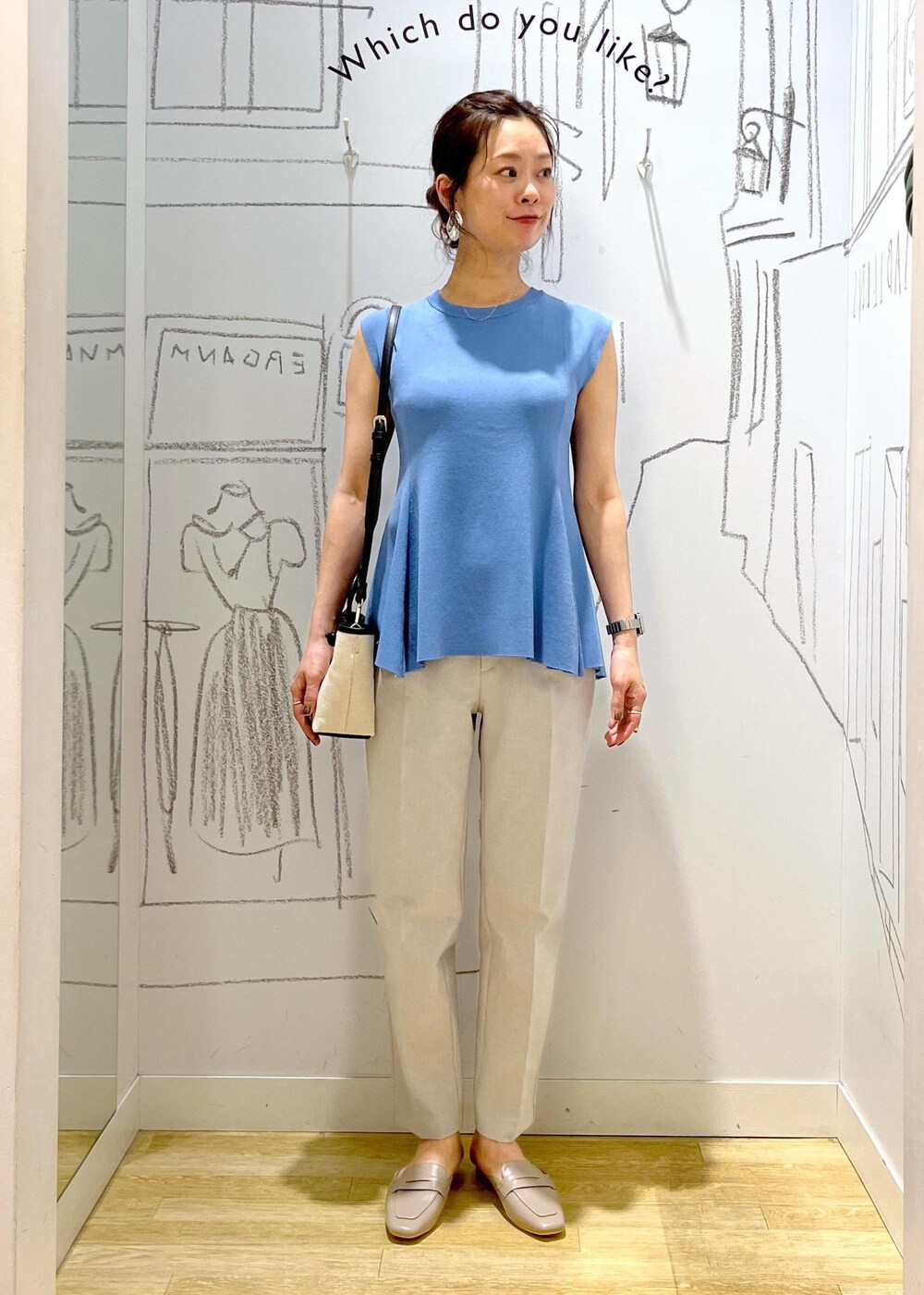 ブルー系のニット/セーター、ブラック系のトートバッグ、グレー系のスラックスを着用したレディースの夏コーディネートの6枚目の写真