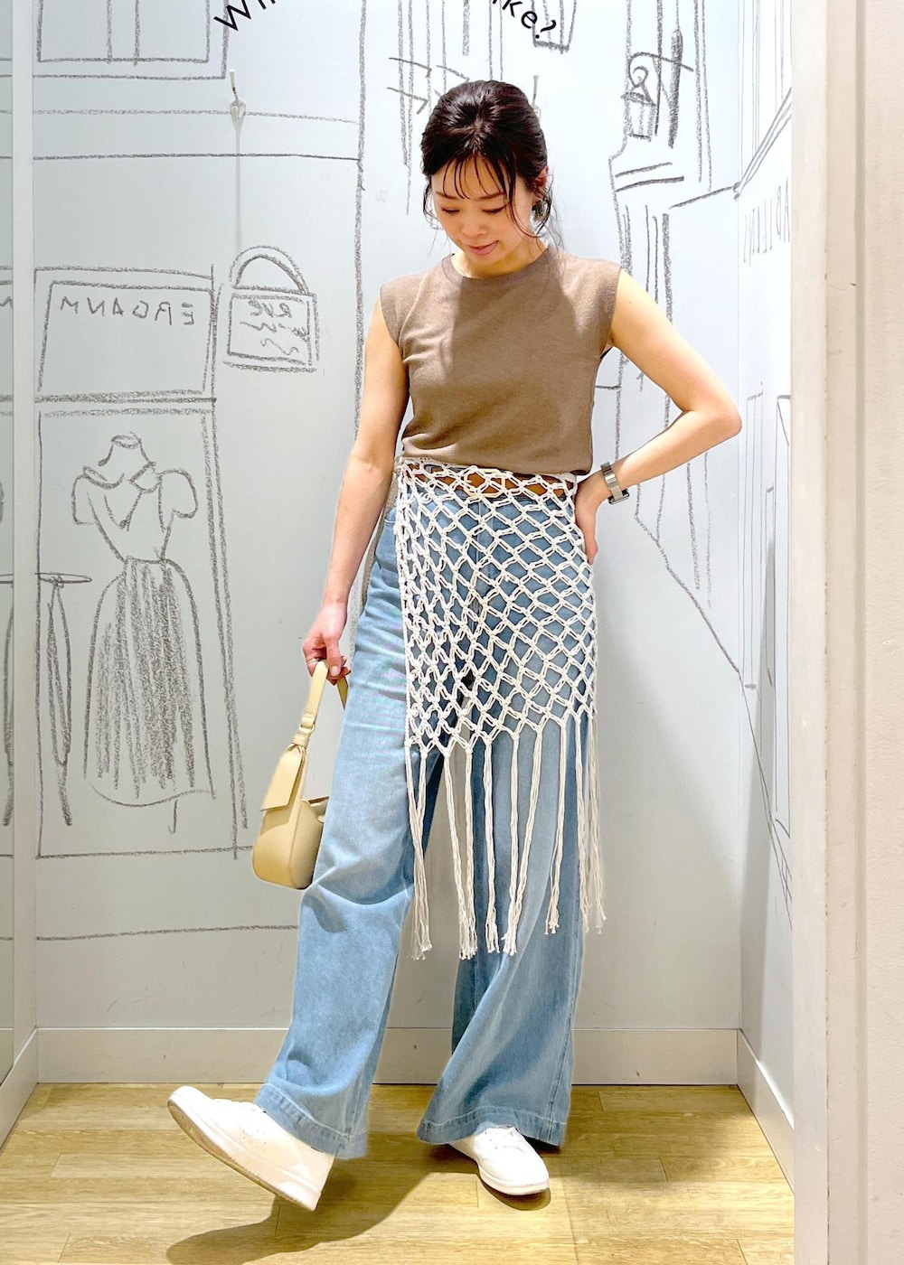 ベージュ系のハンドバッグ、ブルー系のデニムパンツ、ホワイト系のスカートを着用したレディースの春コーディネートの6枚目の写真