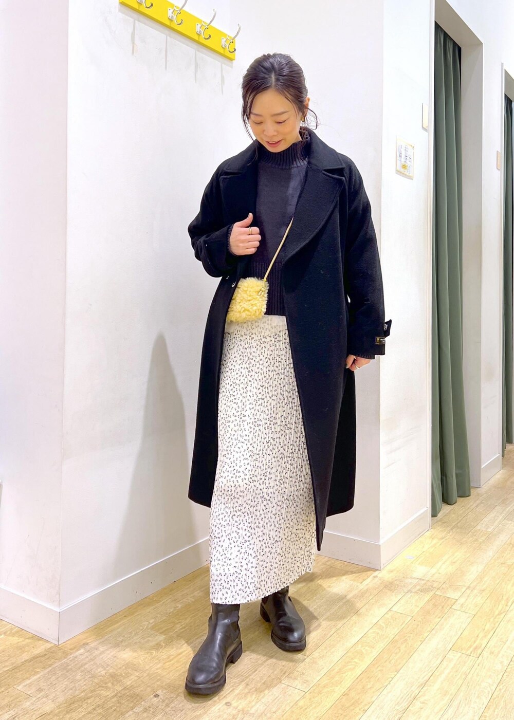 ブラック系のニット/セーター、グレー系のショルダーバッグ、ホワイト系のスカートを着用したレディースの冬コーディネートの3枚目の写真