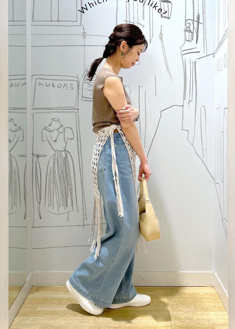 ベージュ系のハンドバッグ、ブルー系のデニムパンツ、ホワイト系のスカートを着用したレディースの春コーディネートの4枚目の写真