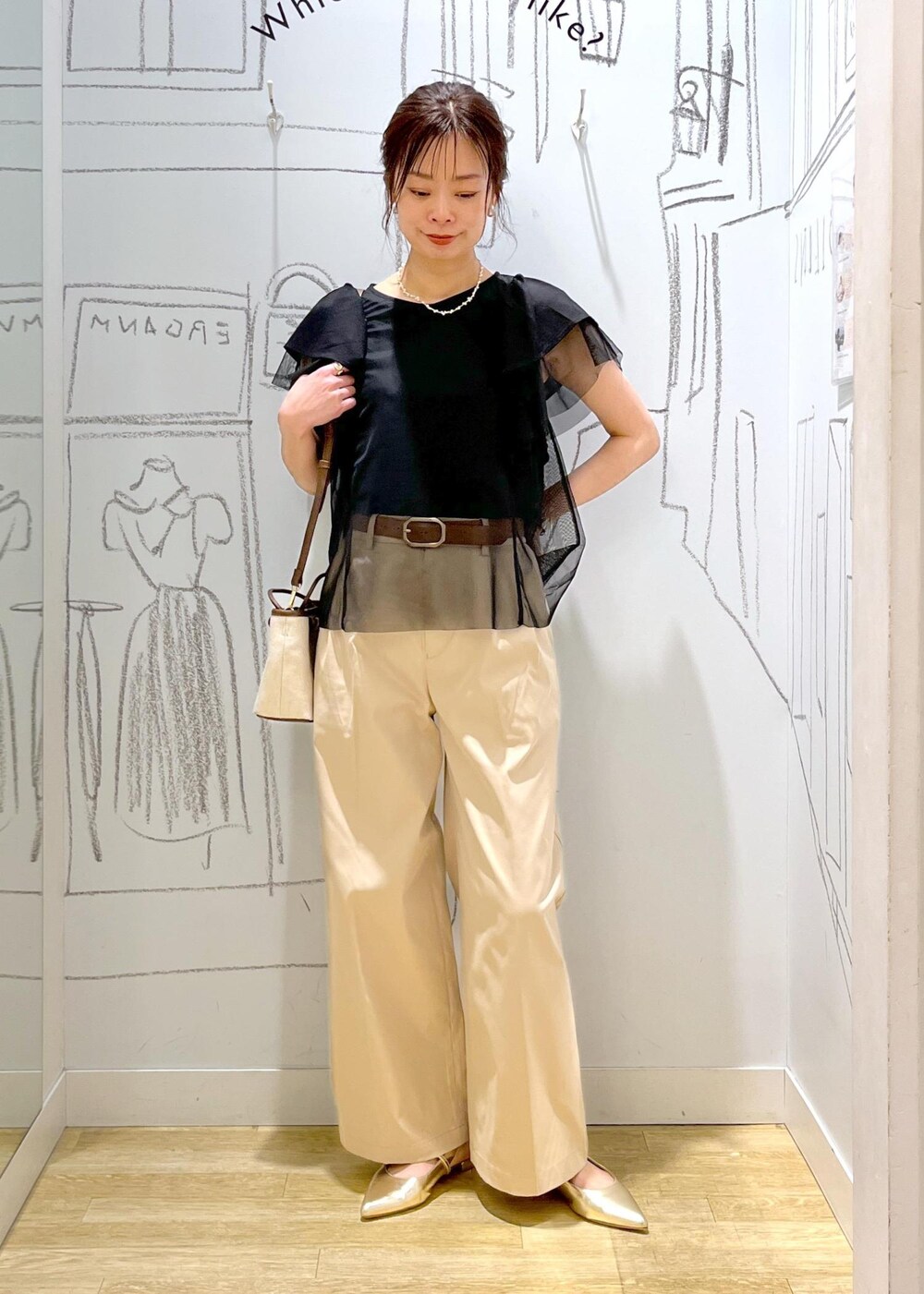 ベージュ系のチノパンツ、ブラウン系のトートバッグ、ブラック系のTシャツ/カットソーを着用したレディースの春コーディネートの3枚目の写真