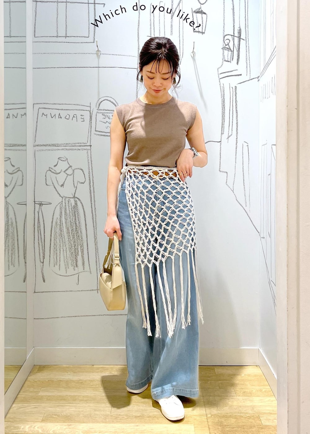 ベージュ系のハンドバッグ、ブルー系のデニムパンツ、ホワイト系のスカートを着用したレディースの春コーディネートの2枚目の写真