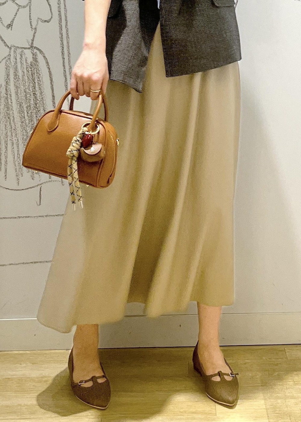 グレー系のテーラードジャケット、ベージュ系のスカート、ブラウン系のパンプスを着用したレディースの秋コーディネートの8枚目の写真