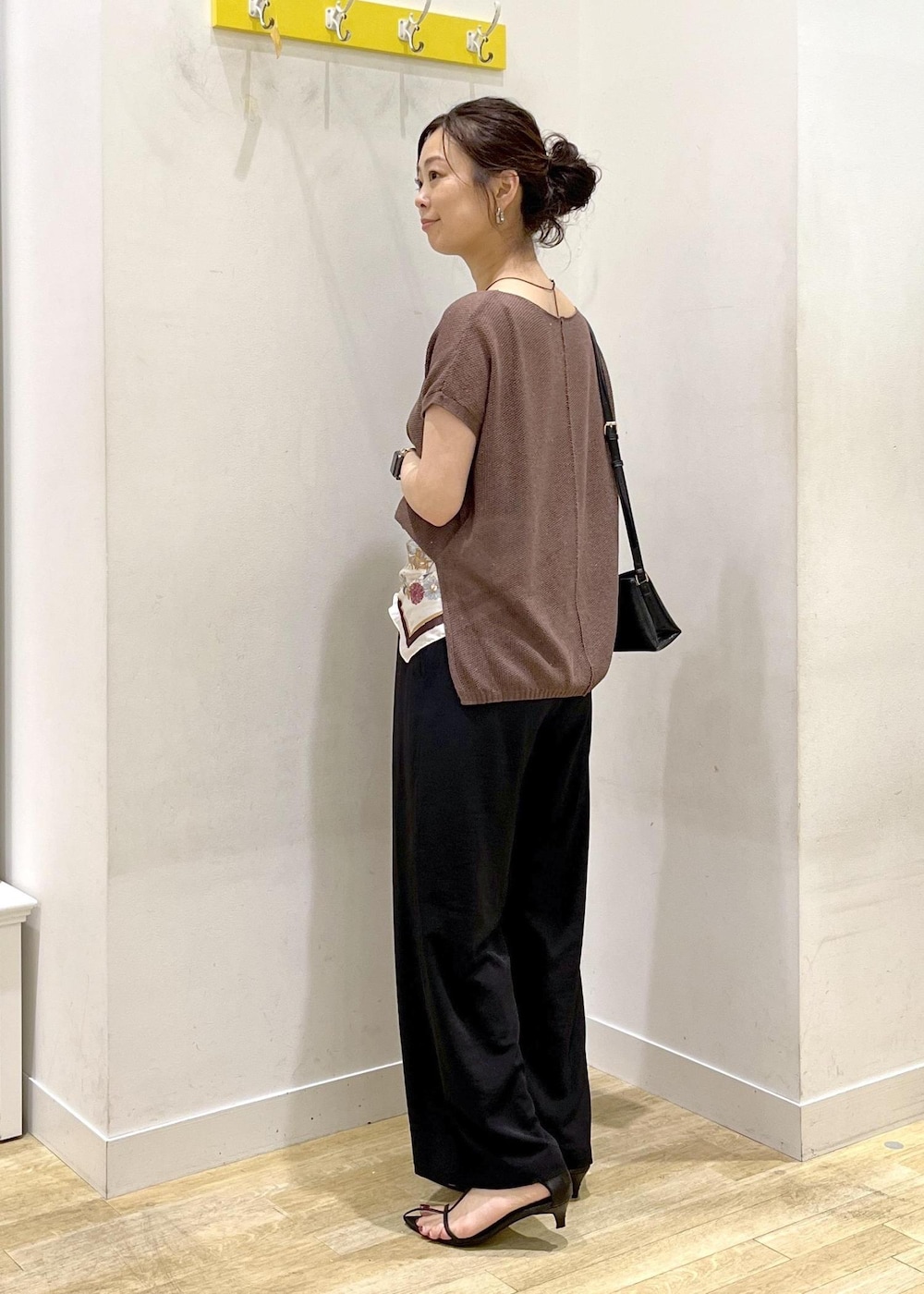ブラック系のショルダーバッグ、ブラック系のその他パンツ、イエロー系のニット/セーターを着用したレディースの夏コーディネートの4枚目の写真