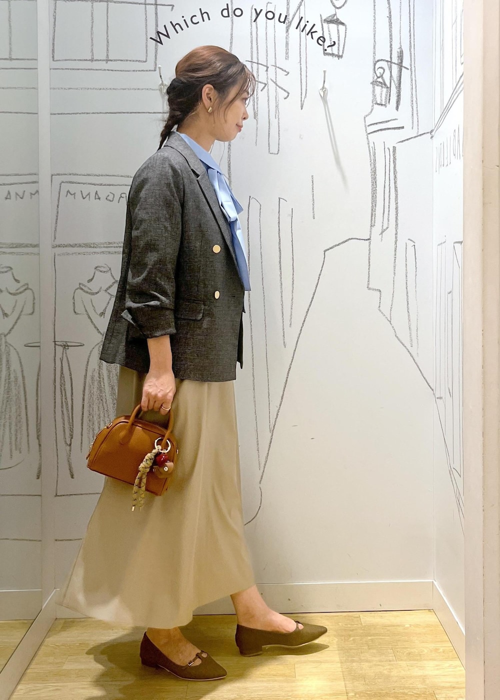グレー系のテーラードジャケット、ベージュ系のスカート、ブラウン系のパンプスを着用したレディースの秋コーディネートの6枚目の写真