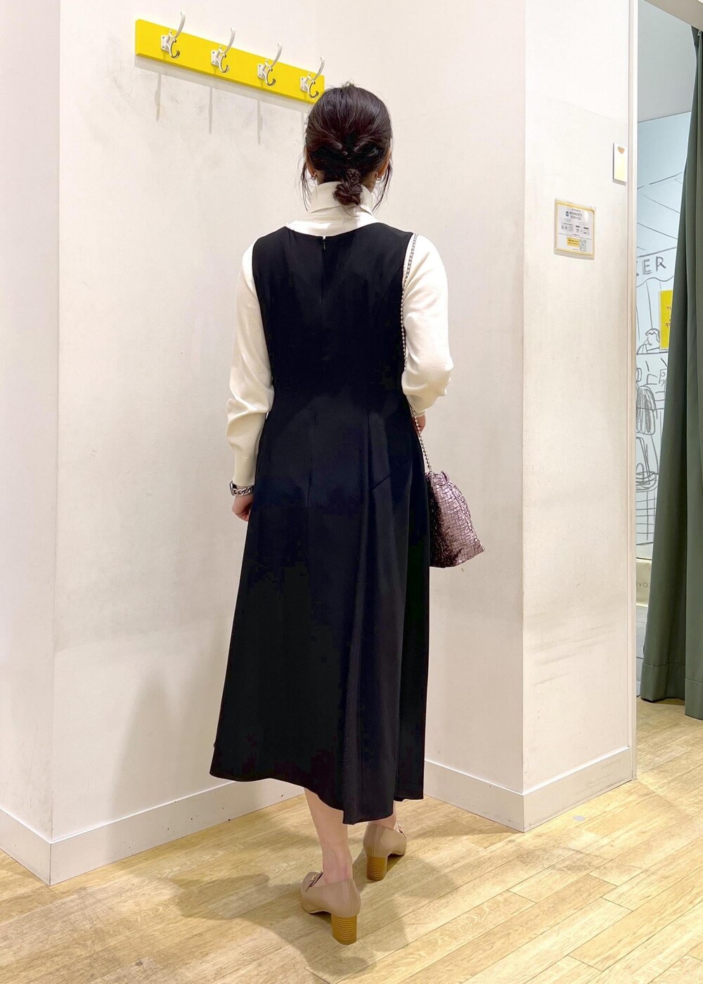 ホワイト系のニット/セーター、ブラック系のドレス、パープル系のショルダーバッグを着用したレディースの冬コーディネートの2枚目の写真