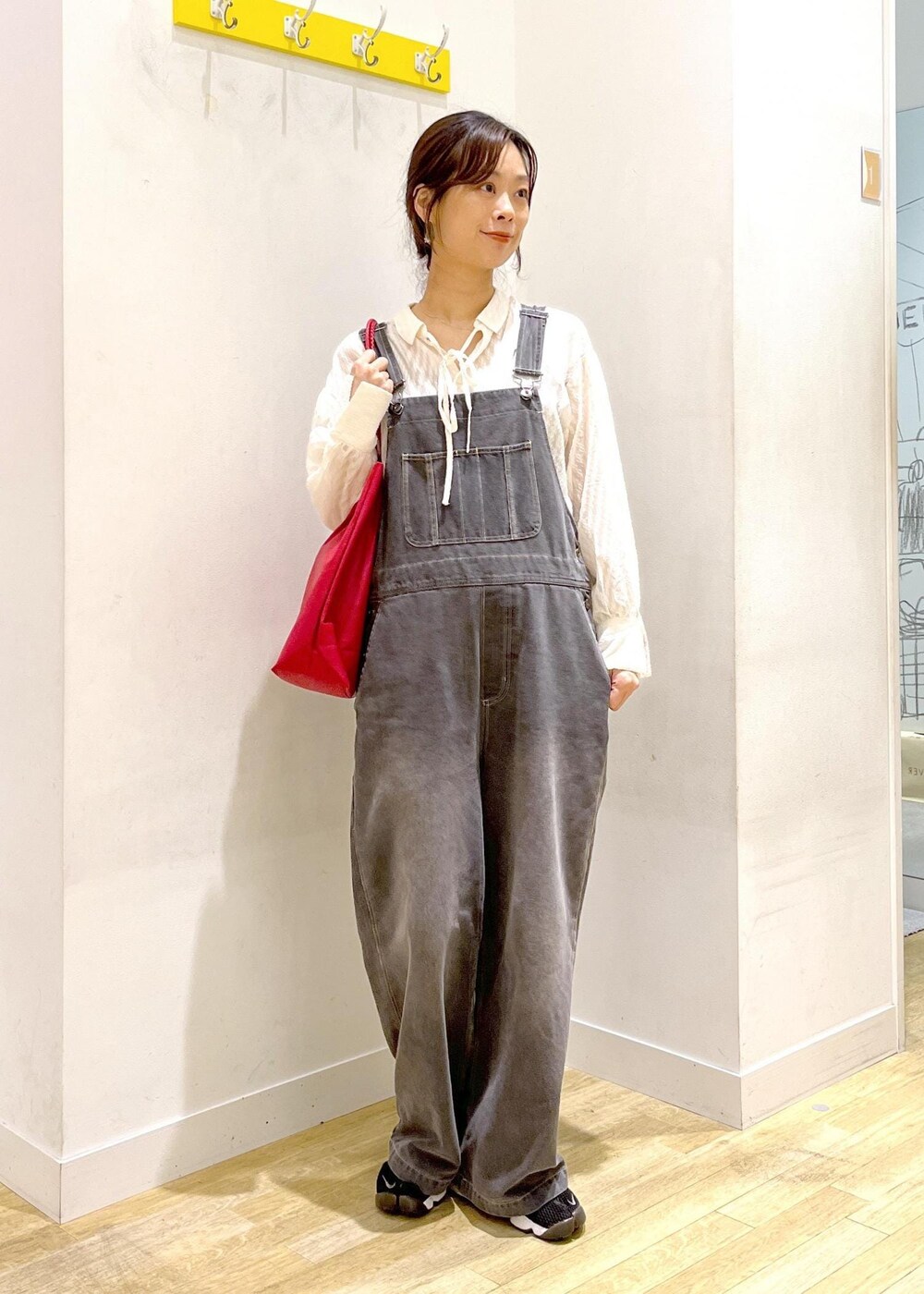 レッド系のトートバッグ、ホワイト系のシャツ/ブラウス、ブラック系のサロペット/オーバーオールを着用したレディースの秋コーディネートの2枚目の写真