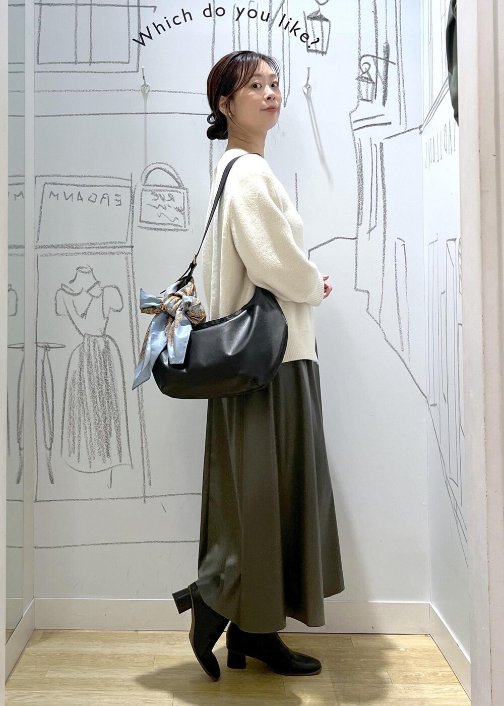 グリーン系のスカート、ホワイト系のカーディガン/ボレロ、ブラック系のショルダーバッグを着用したレディースの秋コーディネートの3枚目の写真