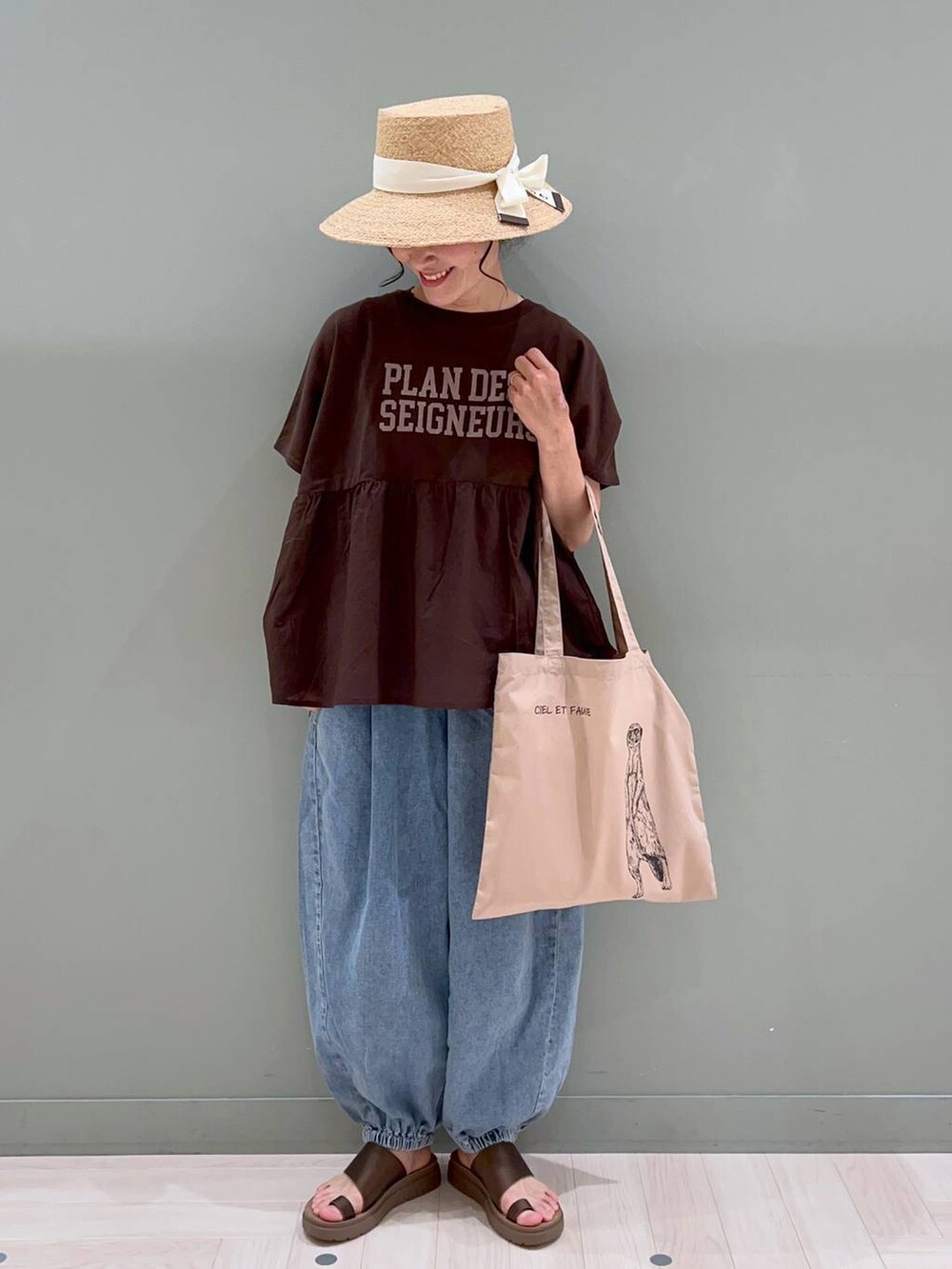 ブラウン系のサンダル、ブルー系のデニムパンツ、ベージュ系のトートバッグを着用したレディースの春コーディネートの2枚目の写真