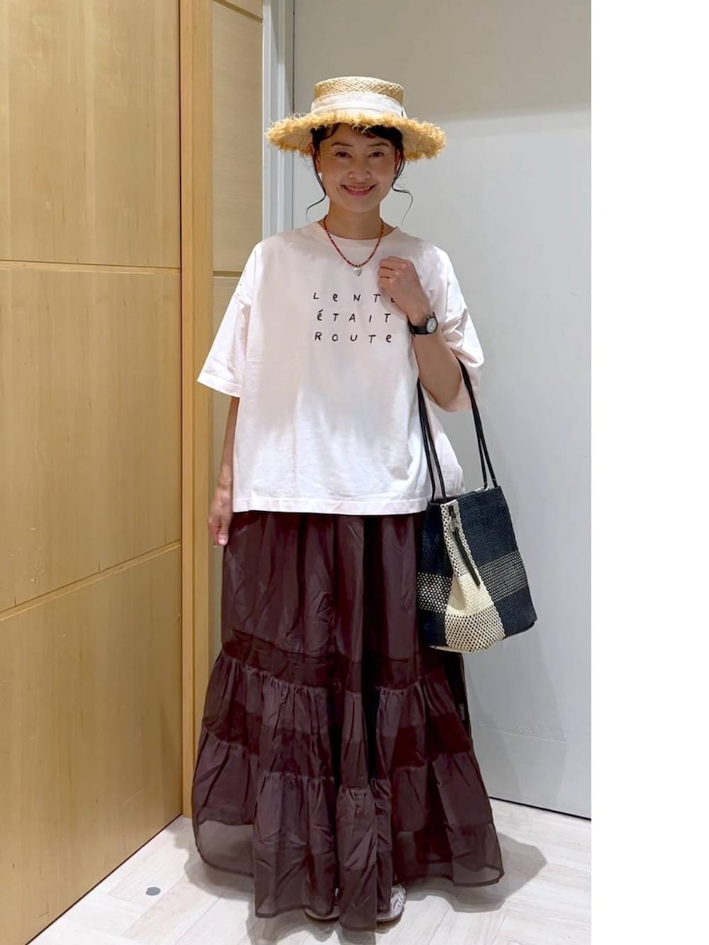 ブラック系のトートバッグ、ピンク系のTシャツ/カットソー、ブラウン系のスカートを着用したレディースの夏コーディネートの5枚目の写真