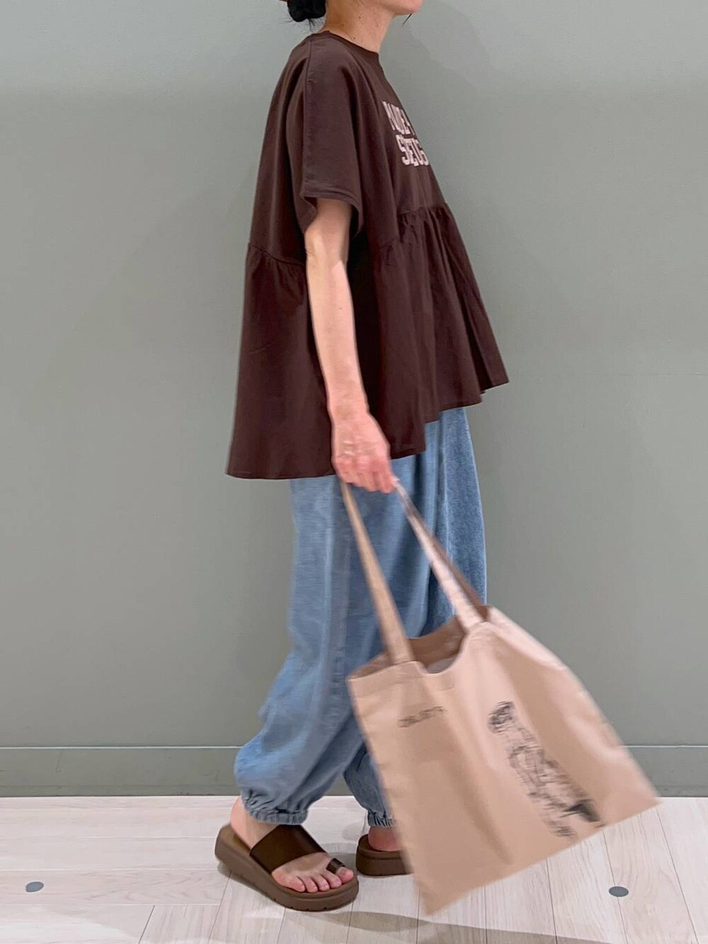ブラウン系のサンダル、ブルー系のデニムパンツ、ベージュ系のトートバッグを着用したレディースの春コーディネートの3枚目の写真