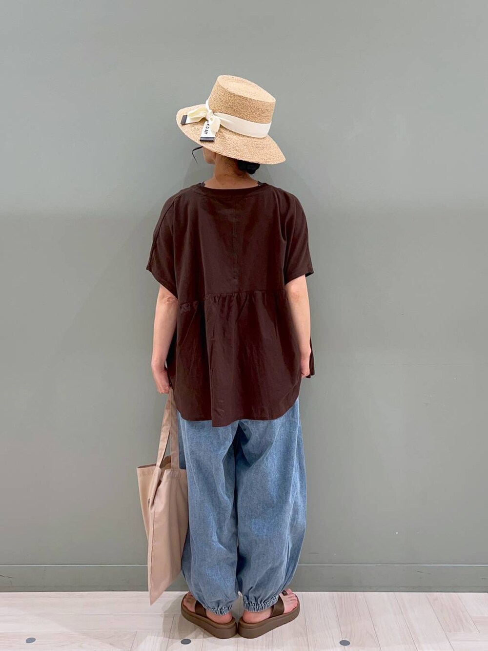 ブラウン系のサンダル、ブルー系のデニムパンツ、ベージュ系のトートバッグを着用したレディースの春コーディネートの4枚目の写真