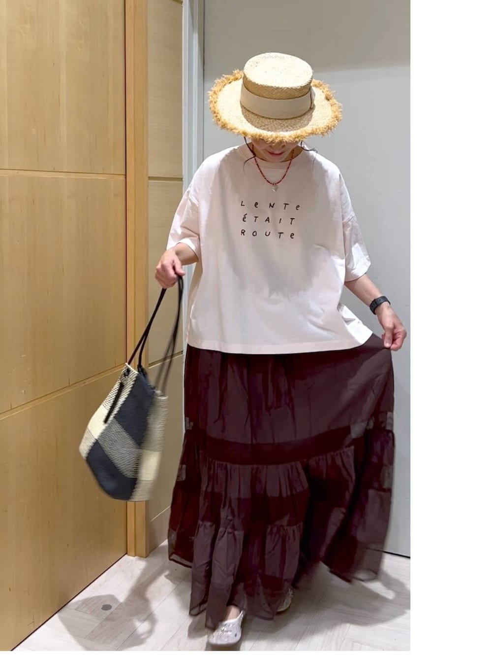 ブラック系のトートバッグ、ピンク系のTシャツ/カットソー、ブラウン系のスカートを着用したレディースの夏コーディネートの6枚目の写真