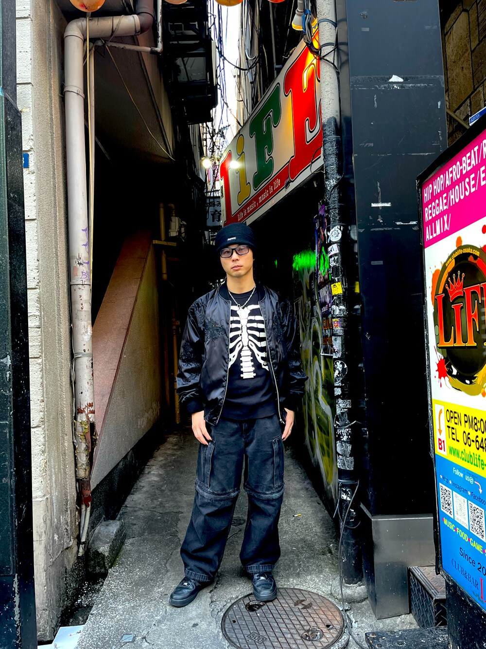 ブラック系のTシャツ/カットソー、ブラック系のデニムパンツ、ブラック系のスニーカーを着用したメンズの秋コーディネートの2枚目の写真