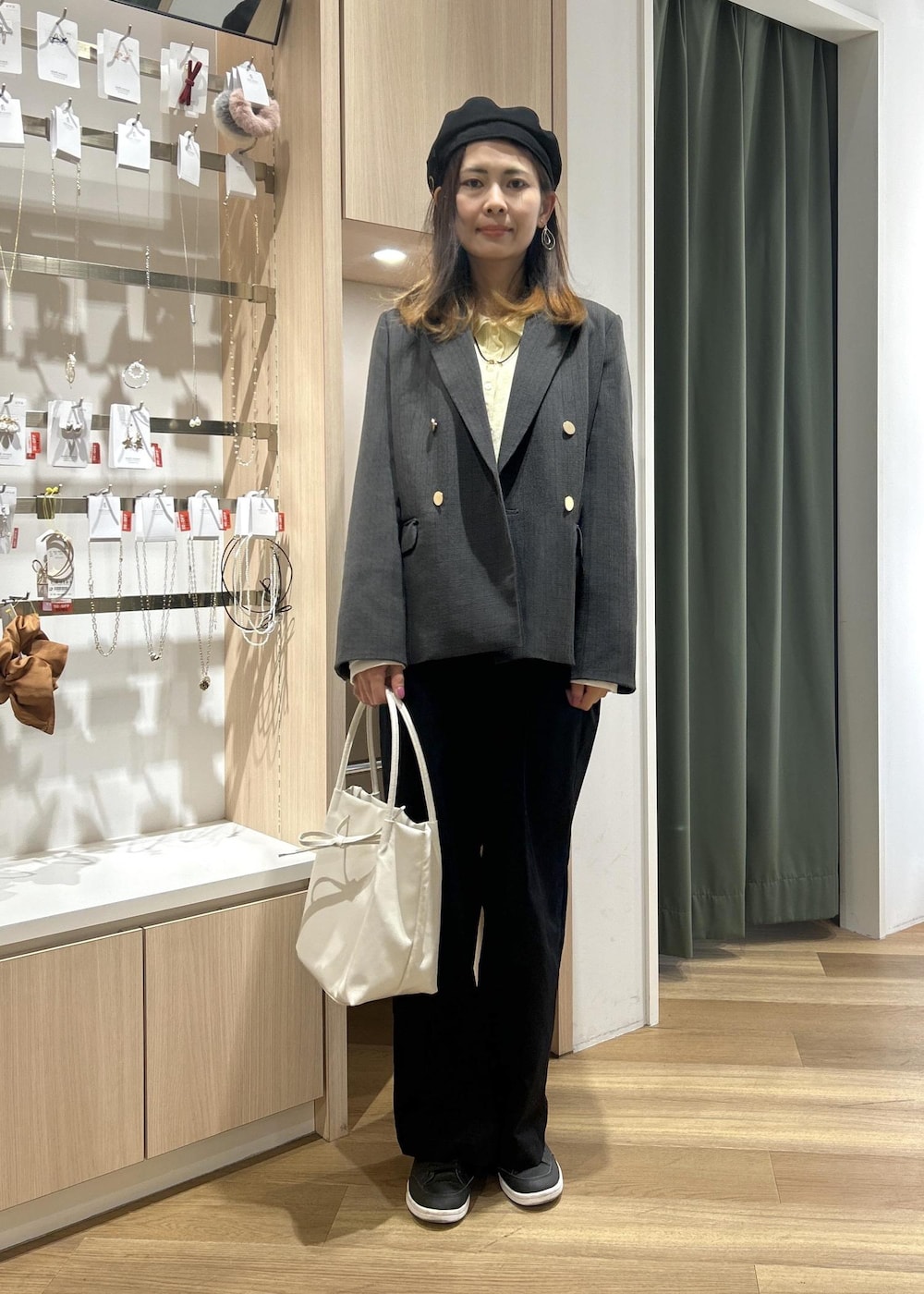 グレー系のテーラードジャケット、ホワイト系のトートバッグ、ブルー系のチノパンツを着用したレディースの冬コーディネートの2枚目の写真