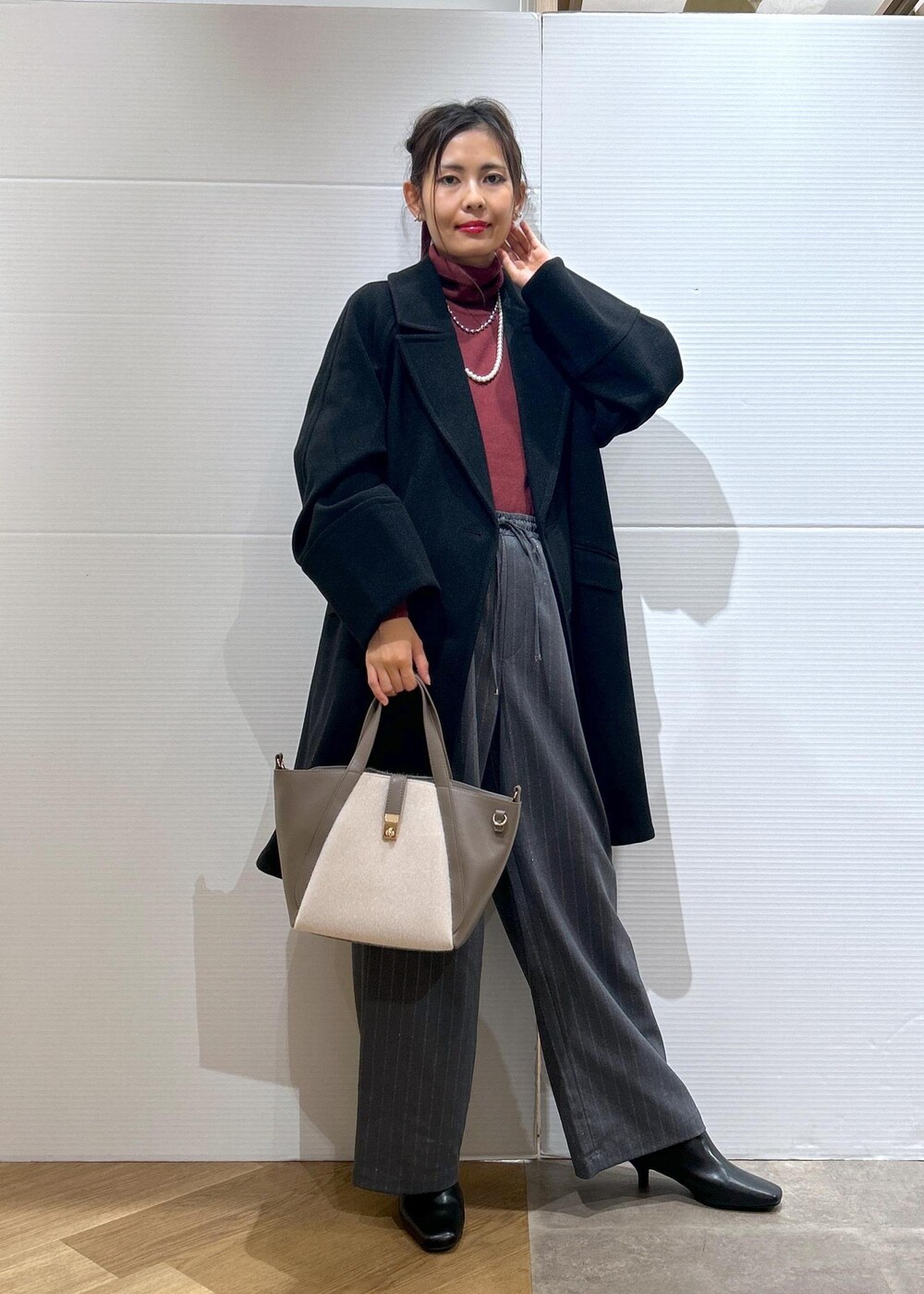 レッド系のニット/セーター、ブラック系のブーツ、グレー系のトートバッグを着用したレディースの秋コーディネートの2枚目の写真