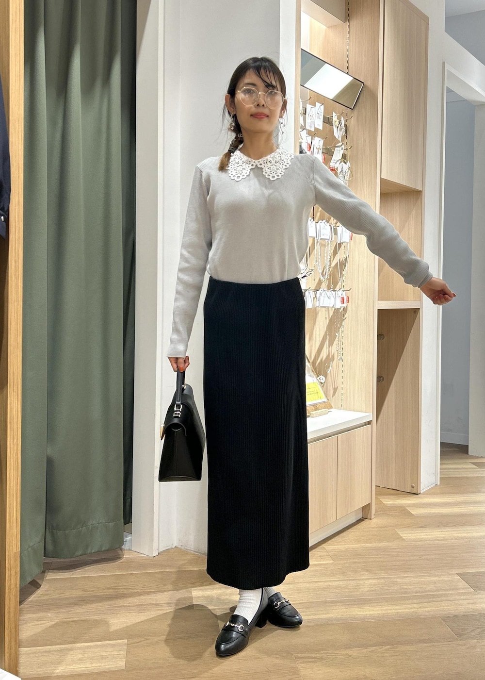 ブラック系のローファー、ブラック系のショルダーバッグ、グレー系のニット/セーターを着用したレディースの冬コーディネートの6枚目の写真