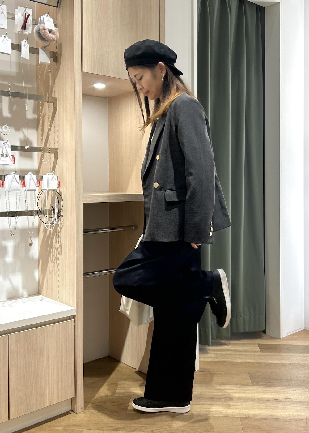 グレー系のテーラードジャケット、ホワイト系のトートバッグ、ブルー系のチノパンツを着用したレディースの冬コーディネートの6枚目の写真