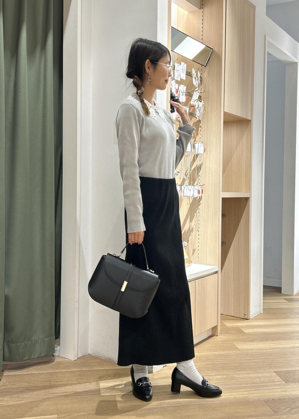 ブラック系のローファー、ブラック系のショルダーバッグ、グレー系のニット/セーターを着用したレディースの冬コーディネートの2枚目の写真