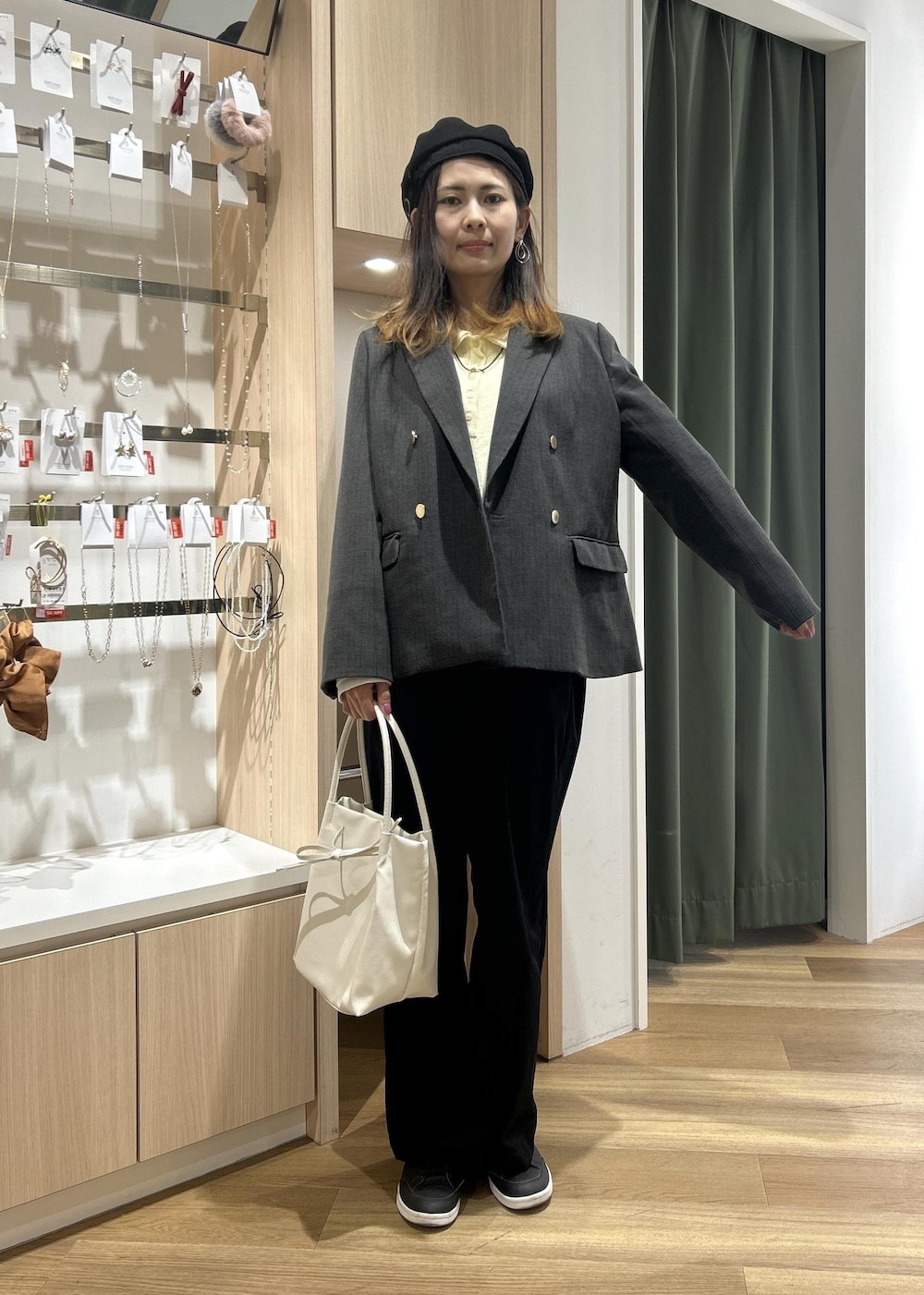 グレー系のテーラードジャケット、ホワイト系のトートバッグ、ブルー系のチノパンツを着用したレディースの冬コーディネートの3枚目の写真