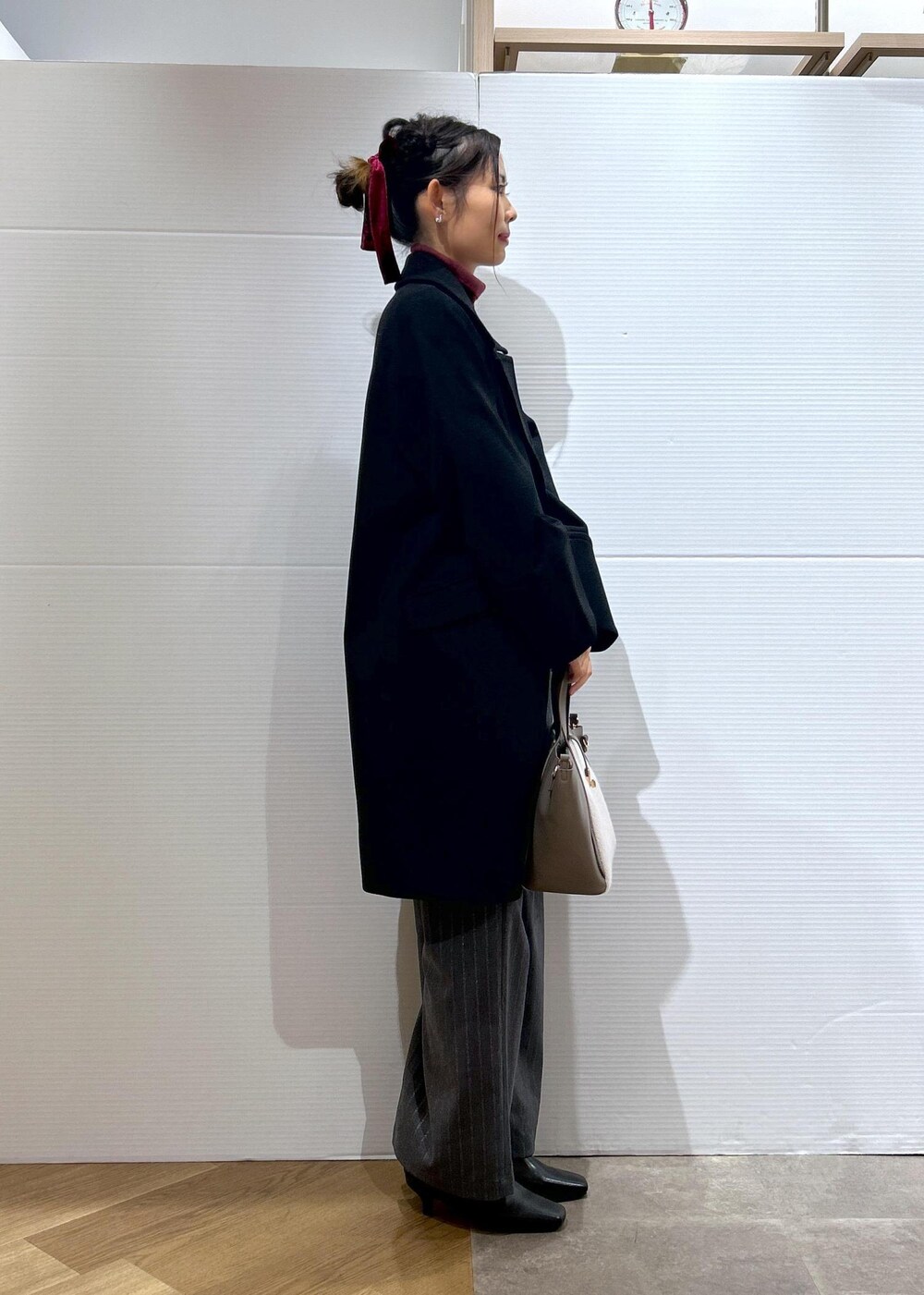 レッド系のニット/セーター、ブラック系のブーツ、グレー系のトートバッグを着用したレディースの秋コーディネートの3枚目の写真