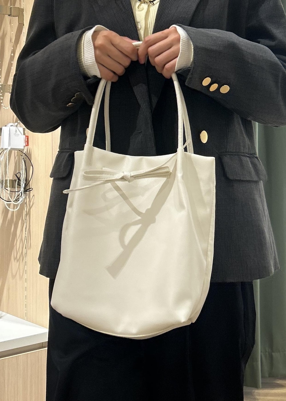 グレー系のテーラードジャケット、ホワイト系のトートバッグ、ブルー系のチノパンツを着用したレディースの冬コーディネートの9枚目の写真