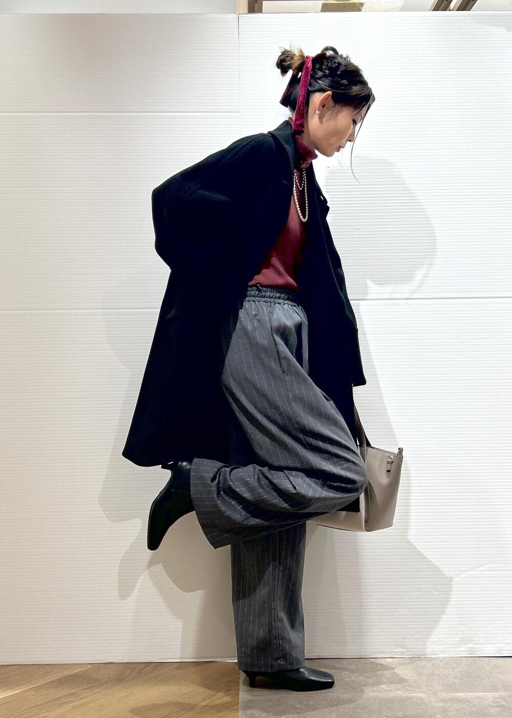 レッド系のニット/セーター、ブラック系のブーツ、グレー系のトートバッグを着用したレディースの秋コーディネートの4枚目の写真