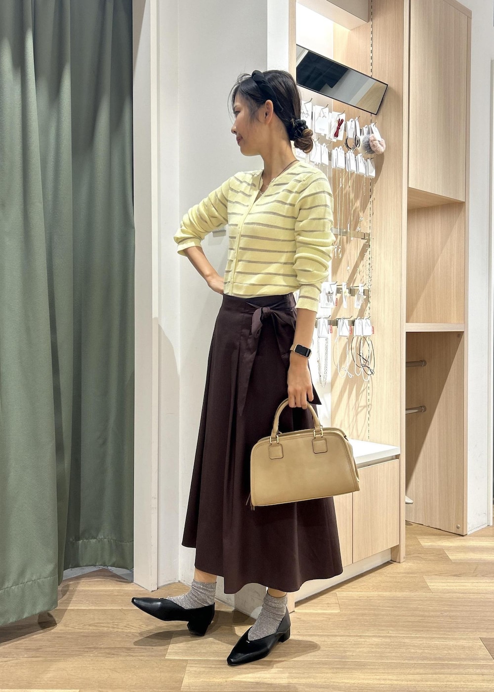 ベージュ系のボストンバッグ、ベージュ系のカーディガン/ボレロ、ブラック系のパンプスを着用したレディースの春コーディネートの2枚目の写真