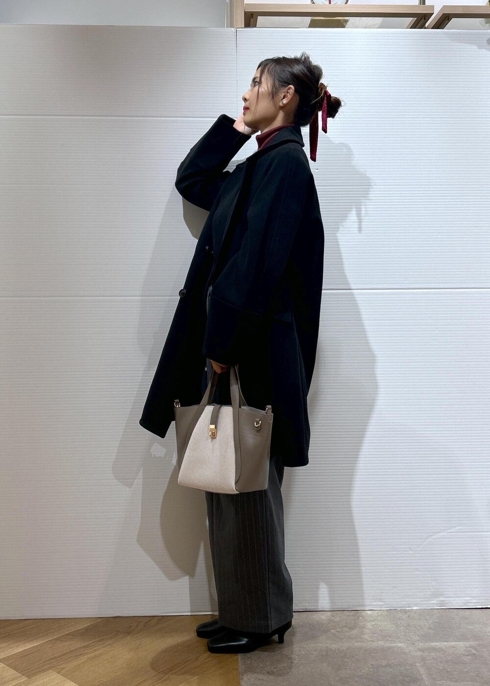 レッド系のニット/セーター、ブラック系のブーツ、グレー系のトートバッグを着用したレディースの秋コーディネートの6枚目の写真