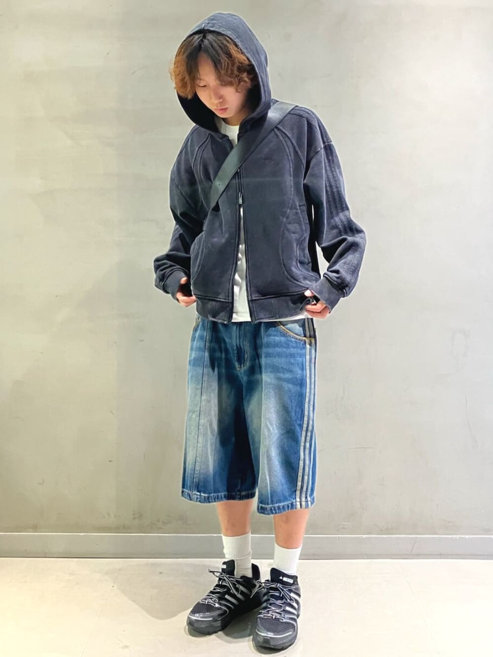 ブラック系のパーカー、ブラック系のショルダーバッグ、ブラック系のスニーカーを着用したメンズの冬コーディネートの2枚目の写真