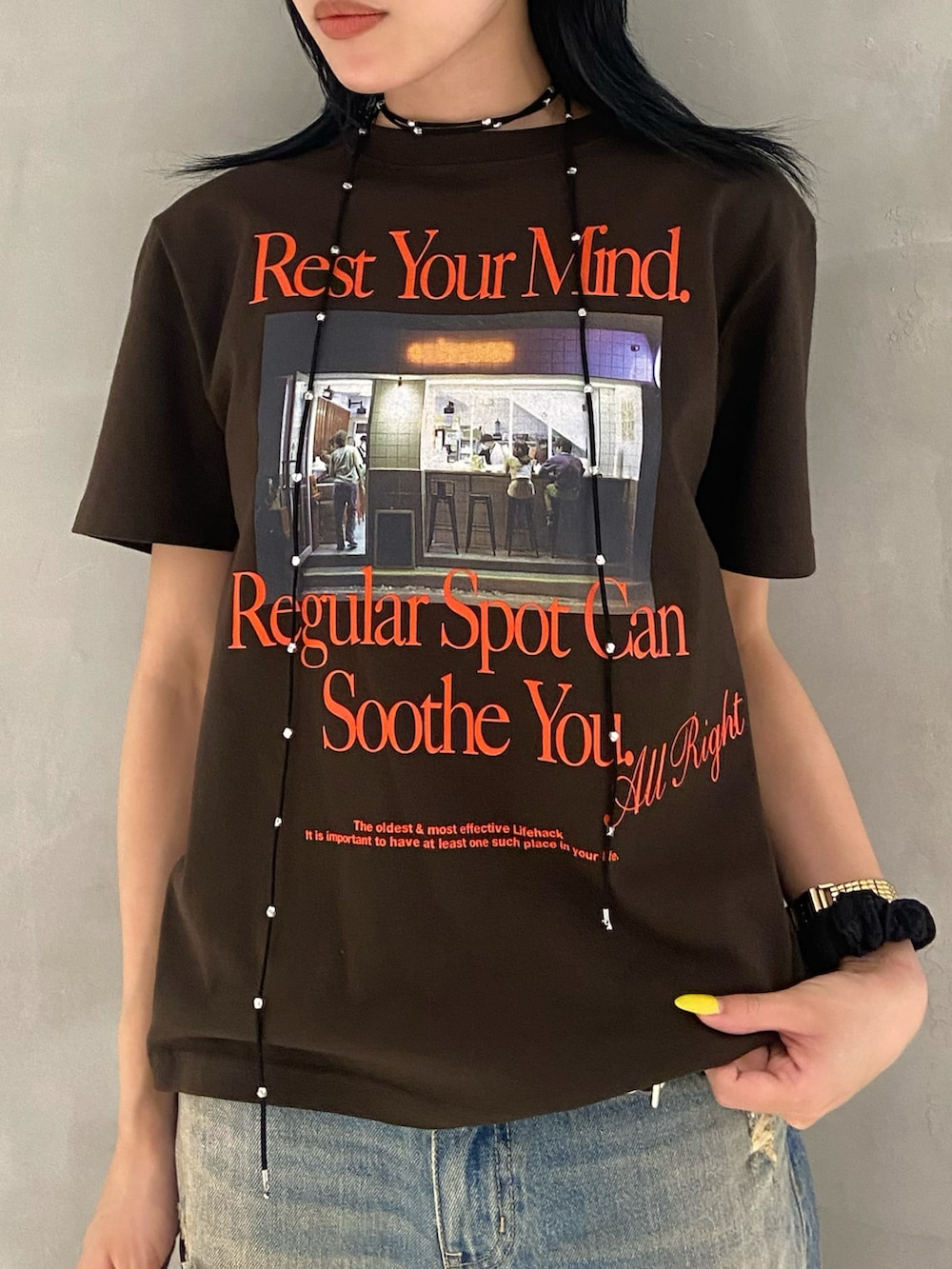 ブラウン系のTシャツ/カットソー、ブルー系のデニムパンツ、ブラック系のスニーカーを着用したレディースの夏コーディネートの2枚目の写真