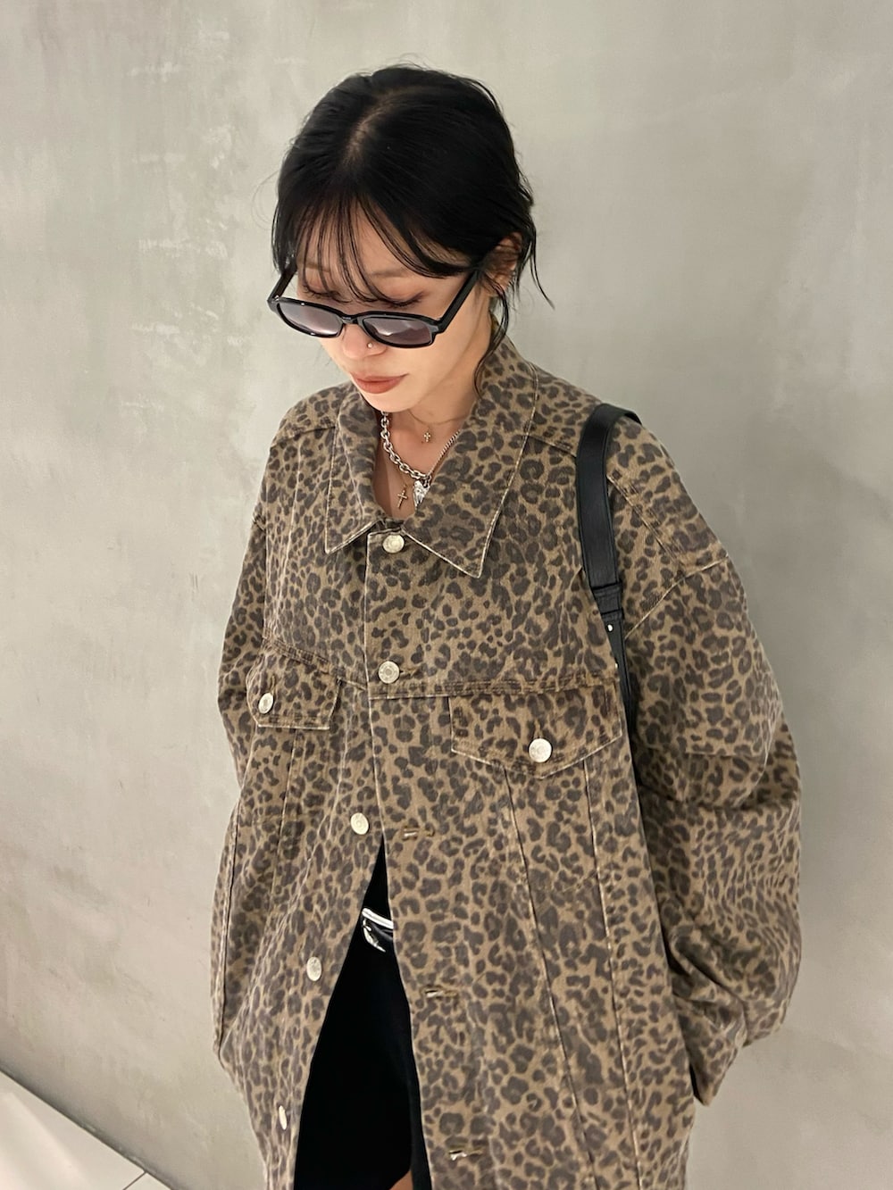 ブラウン系のデニムジャケット、ブラック系のスラックス、ブラック系のブーツを着用したレディースの秋コーディネートの2枚目の写真