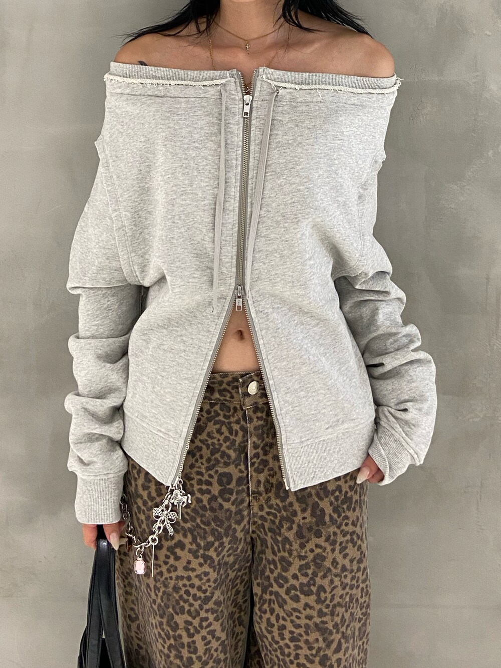 グレー系のスウェット、ブラック系のショルダーバッグ、ブラウン系のデニムパンツを着用したレディースの秋コーディネートの2枚目の写真