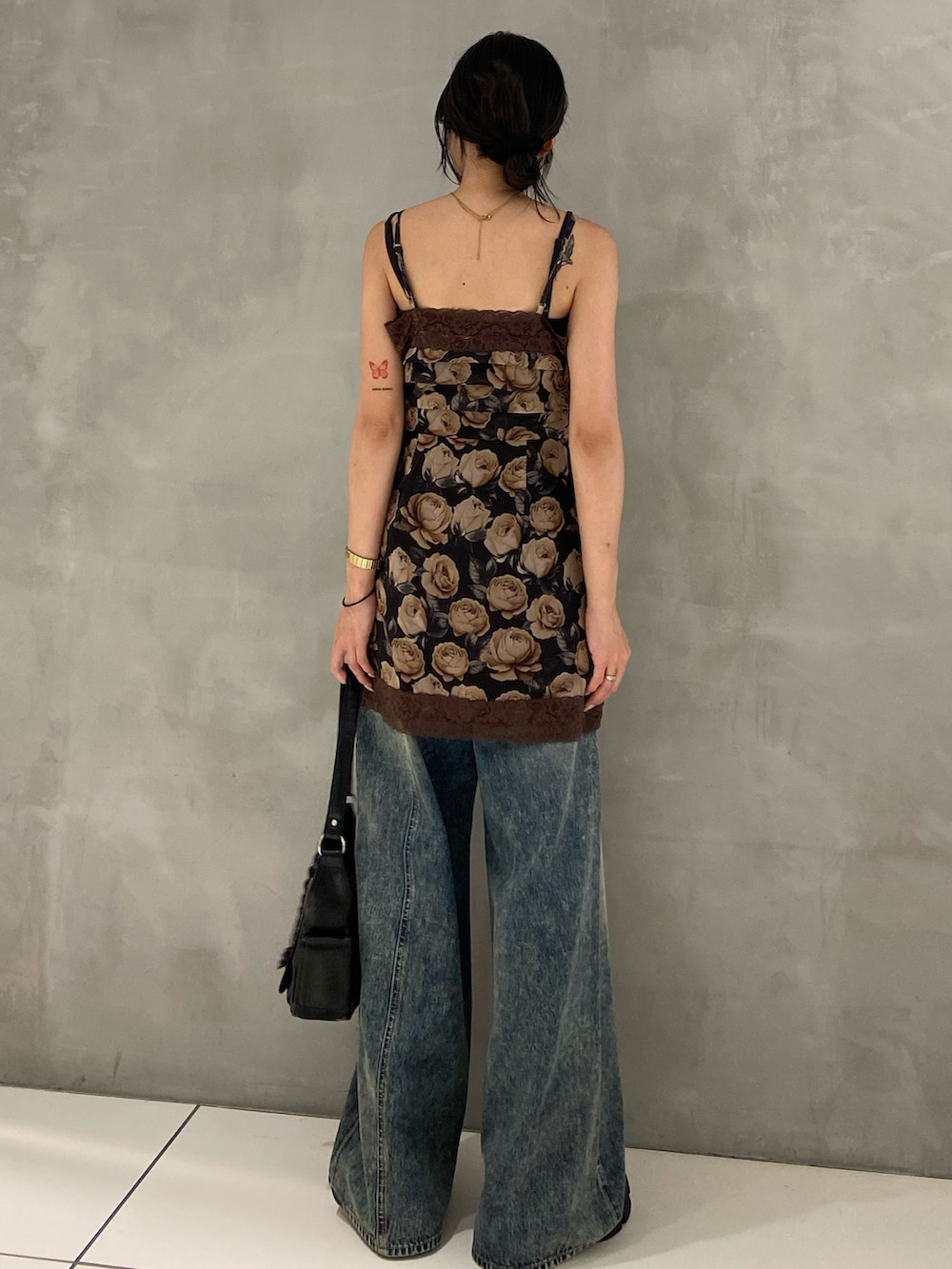 ブラウン系のワンピース、ブルー系のデニムパンツ、ブラック系のブーツを着用したレディースの夏コーディネートの2枚目の写真