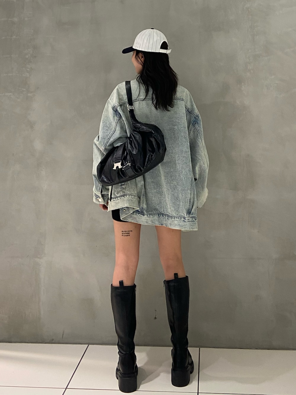 ブルー系のデニムジャケット、ブラック系のスラックス、ブラック系のブーツを着用したレディースの秋コーディネートの2枚目の写真