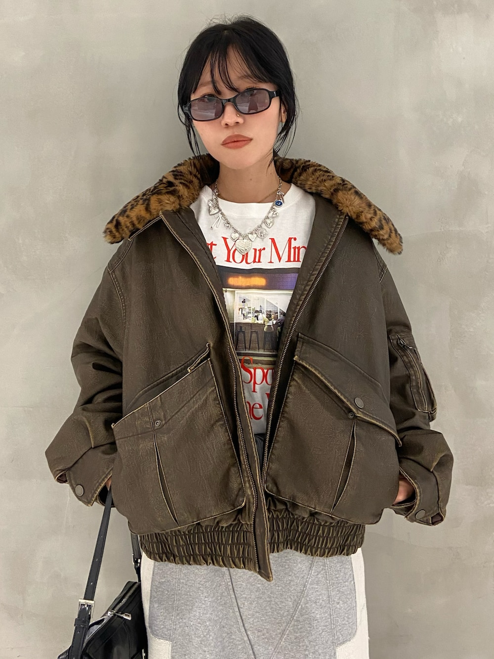 ブラック系のショルダーバッグ、ホワイト系のTシャツ/カットソー、ブラウン系のブルゾンを着用したレディースの夏コーディネートの3枚目の写真