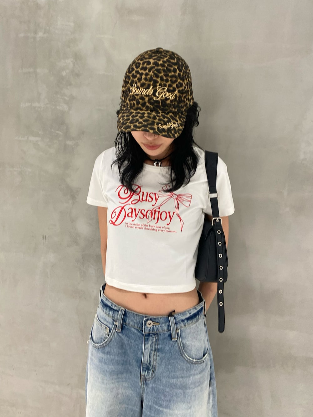 ブラック系のブーツ、ブルー系のデニムパンツ、ブラック系のハンドバッグを着用したレディースの夏コーディネートの2枚目の写真