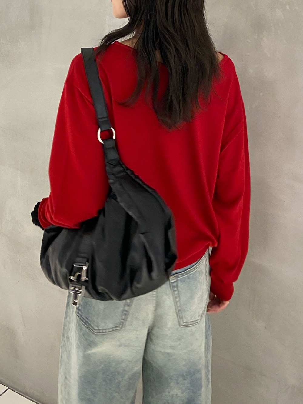 レッド系のニット/セーター、ブラック系のトートバッグ、ブルー系のデニムパンツを着用したレディースの秋コーディネートの3枚目の写真